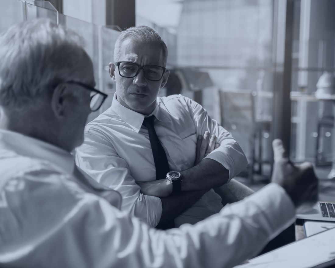 2 senior executives in discussion at a meeting table.